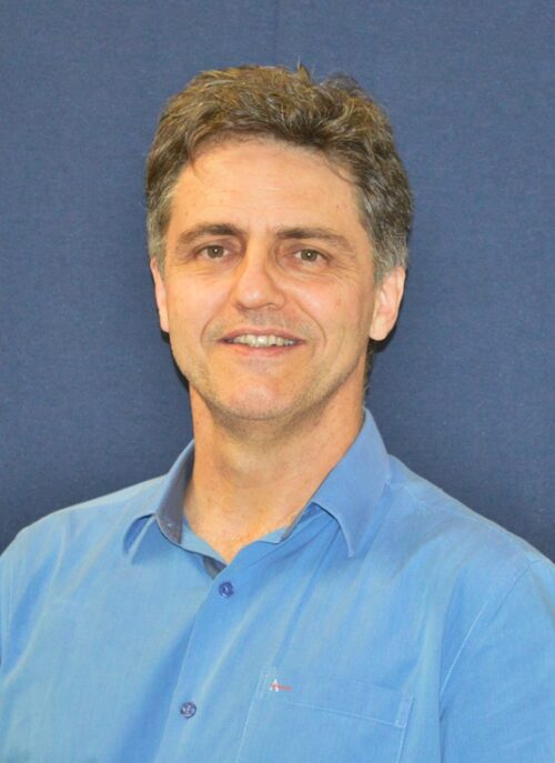 foto de um homem branco que usa camisa azul clara e aparece do peito para cima